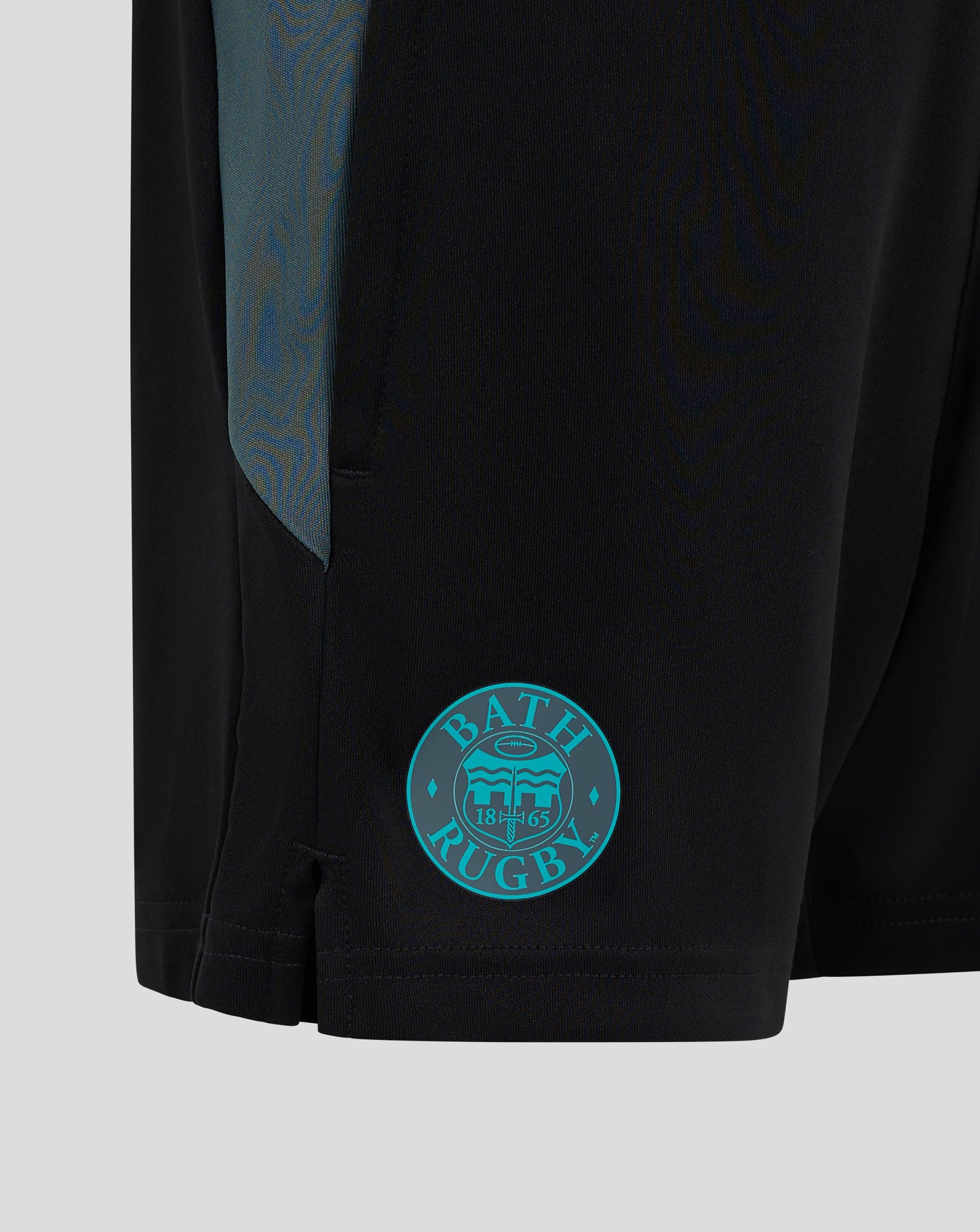 Close up of Bath Rugby Junior shorts in black with teal side panel and Bath Rugby crest on the right thigh