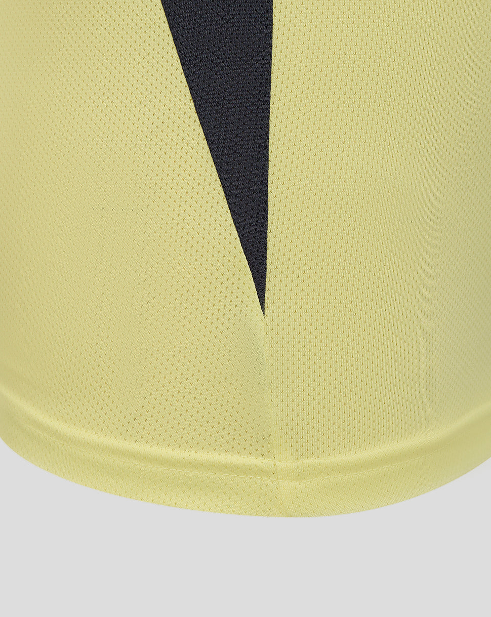 Close-up of the pale yellow fabric with a dark navy V shaped panel and textured mesh material at the hem.