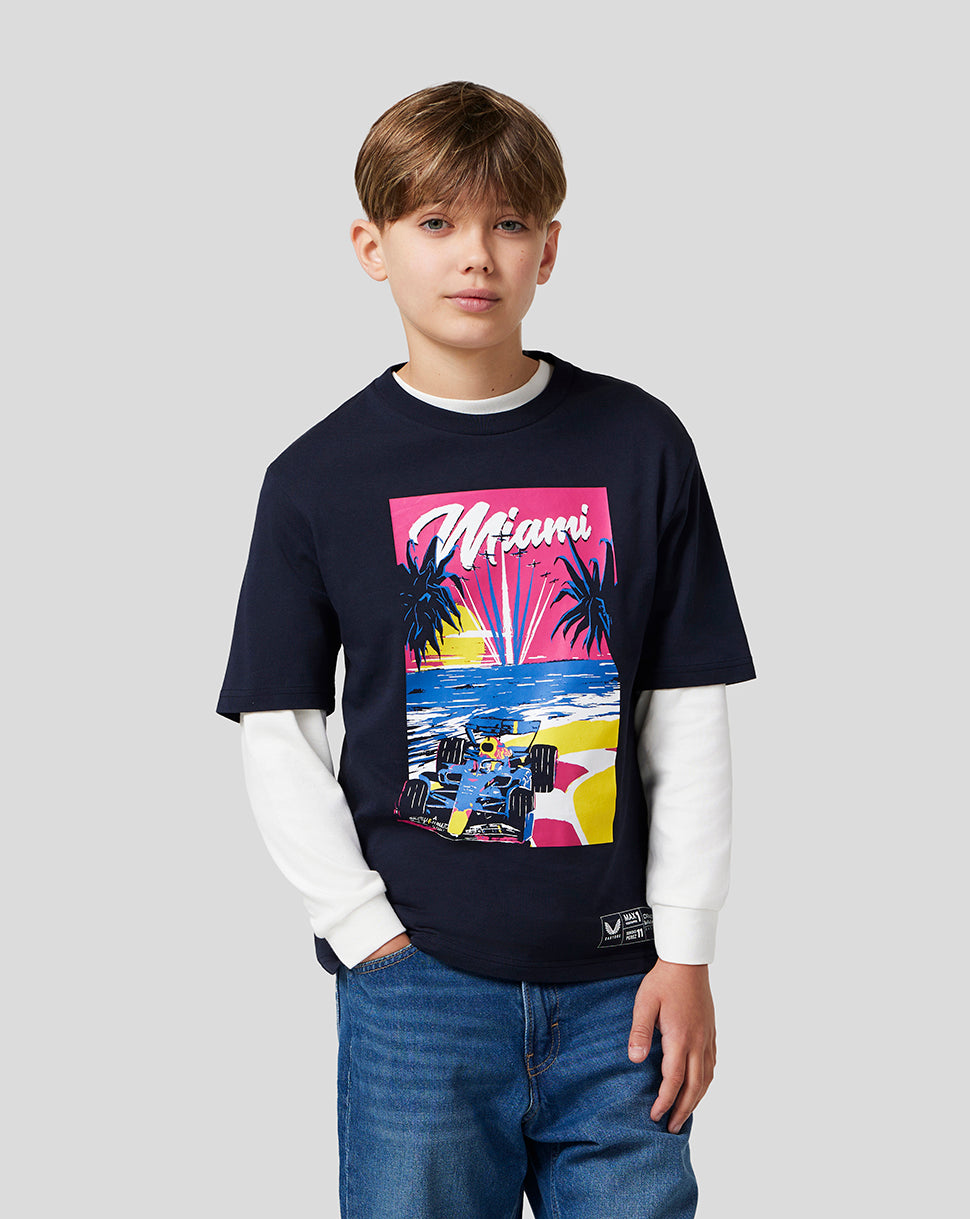 Young boy wearing a navy Miami graphic T shirt from Oracle Red Bull Racing with a white long sleeve underlayer