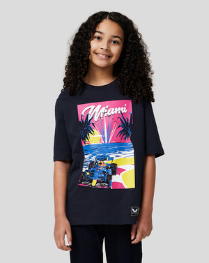 Smiling girl in navy Miami graphic T shirt with a colorful retro race car and palm trees.