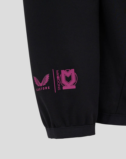 Detail of the black Mk Dons travel pants leg with pink logo and Castore emblem at the cuff