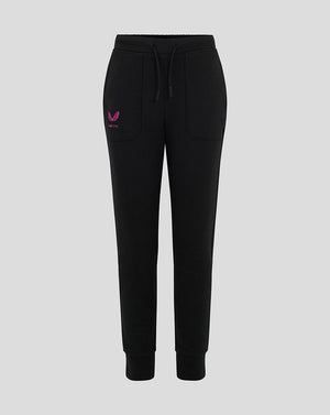 Front view of black Mk Dons junior travel pants with pink winged logo on the left thigh