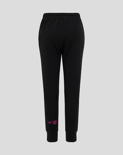 Back view of black Mk Dons junior travel pants with pink logo near the lower leg