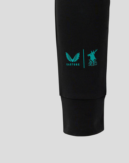 Close-up of black travel pant leg with teal logo on the lower calf.