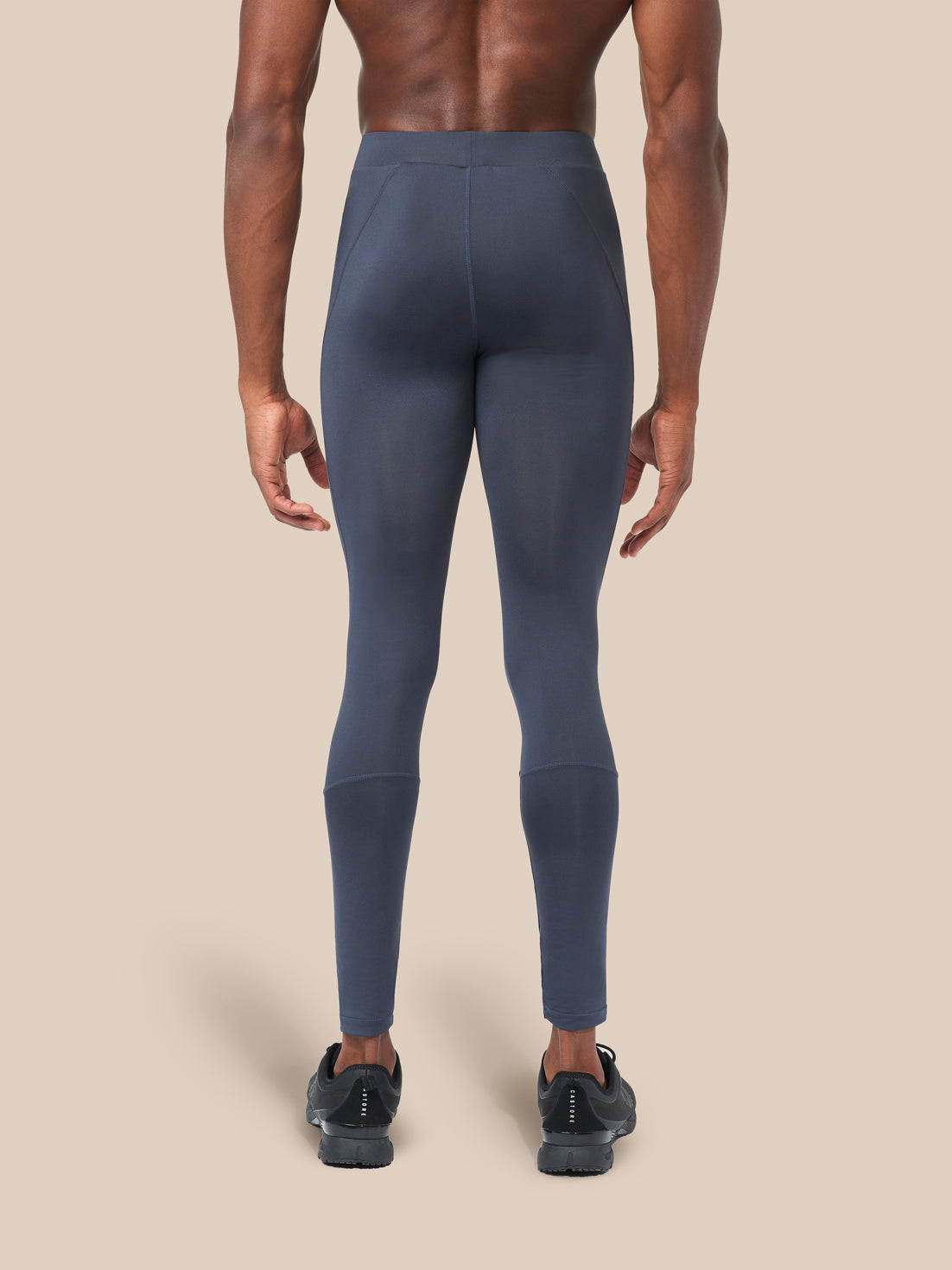 Back view of navy leggings on a model with visible waistband and seam panels
