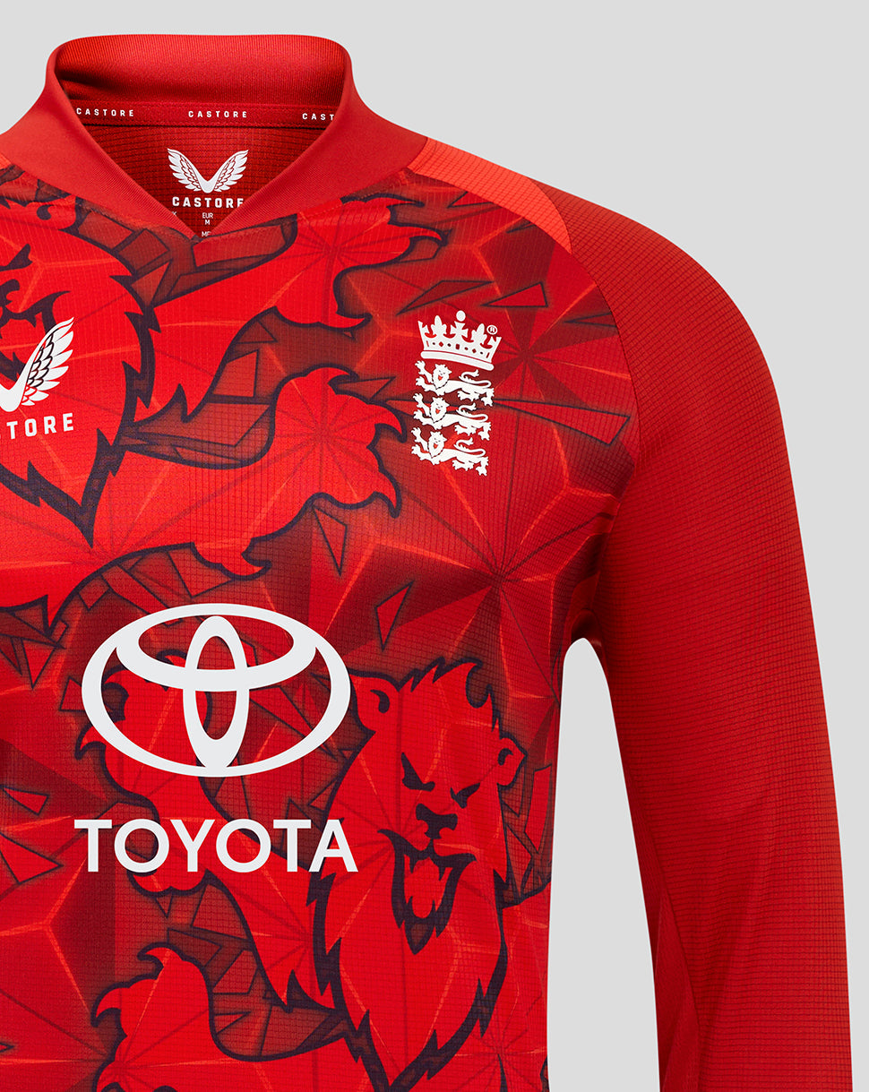 Close up of England T20 Pro long sleeve shirt with raglan sleeves, Three Lions crest and Toyota logo on red patterned fabric