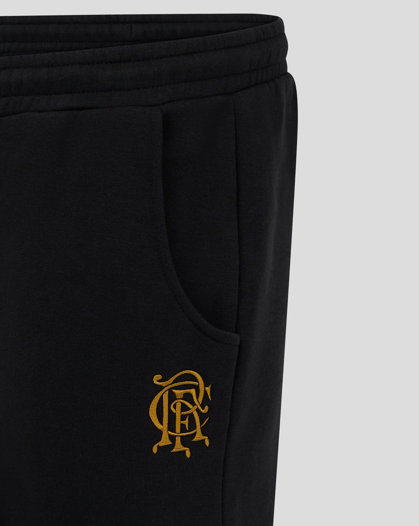 Close up of the back hip area on black Rangers FC joggers showing gold crest embroidery beside the pocket
