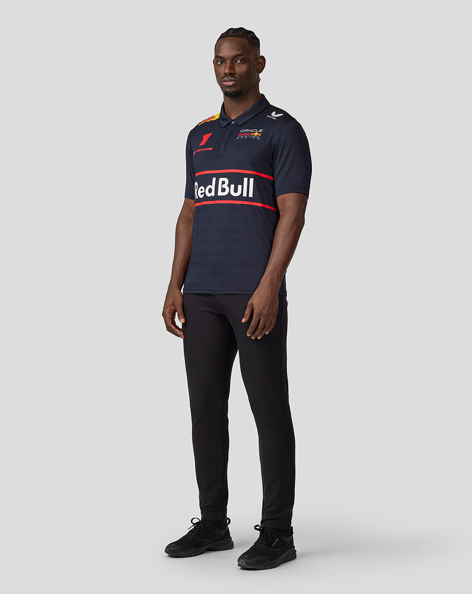 Full length view of a male model in a navy Oracle Red Bull Racing polo with a large Red Bull across the chest and branding