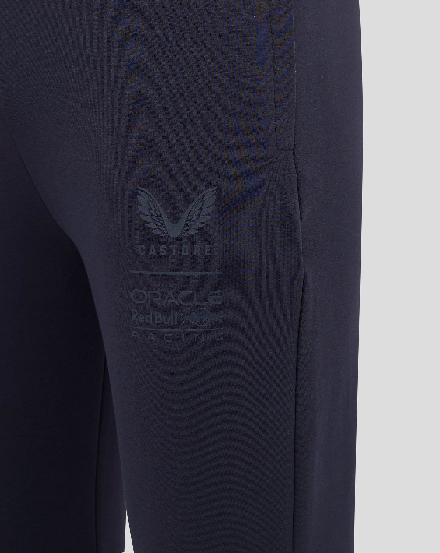 Close-up of navy jogger leg showing large Castore branding and Oracle Red Bull Racing logo.