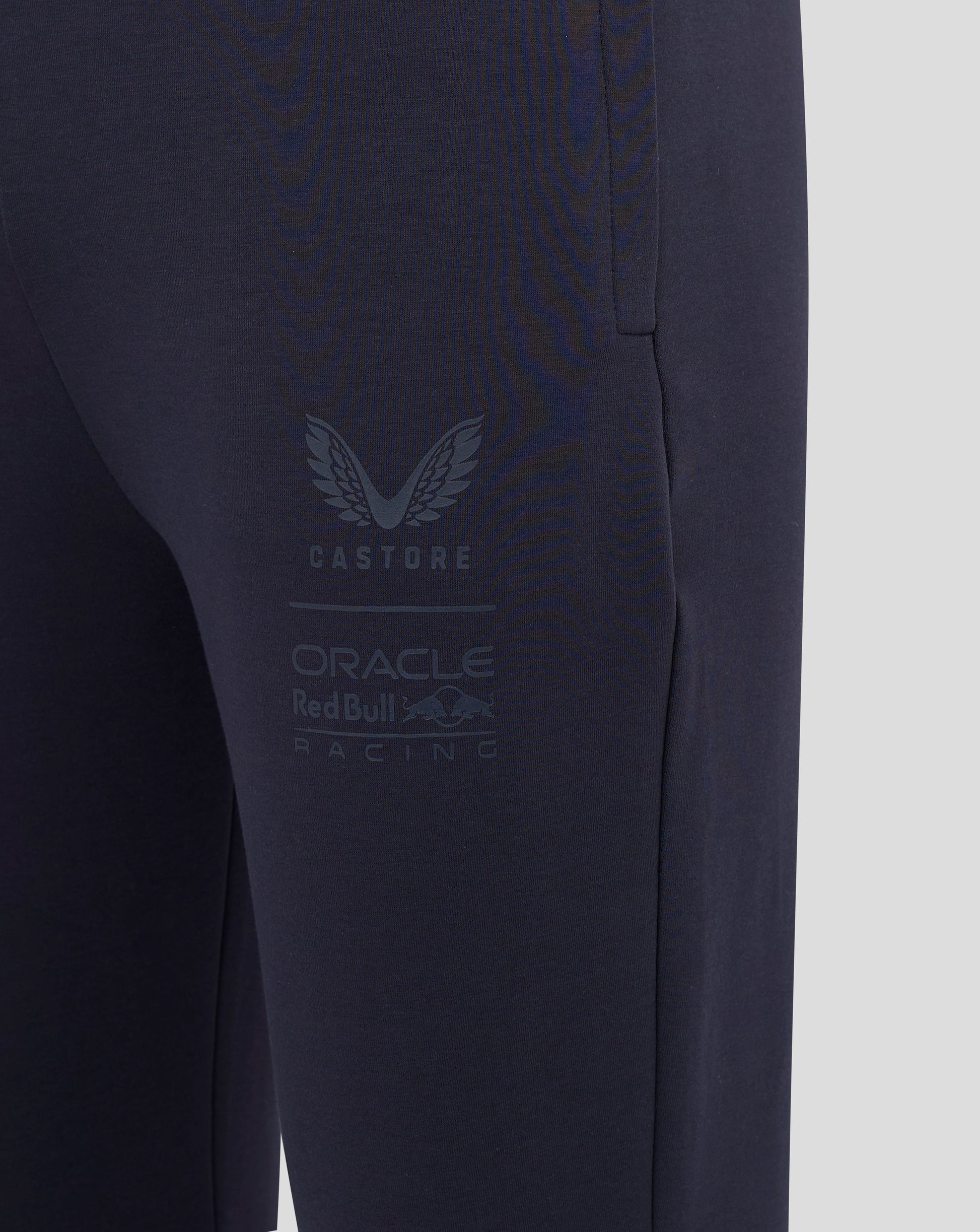 Close-up of navy jogger leg showing large Castore branding and Oracle Red Bull Racing logo.