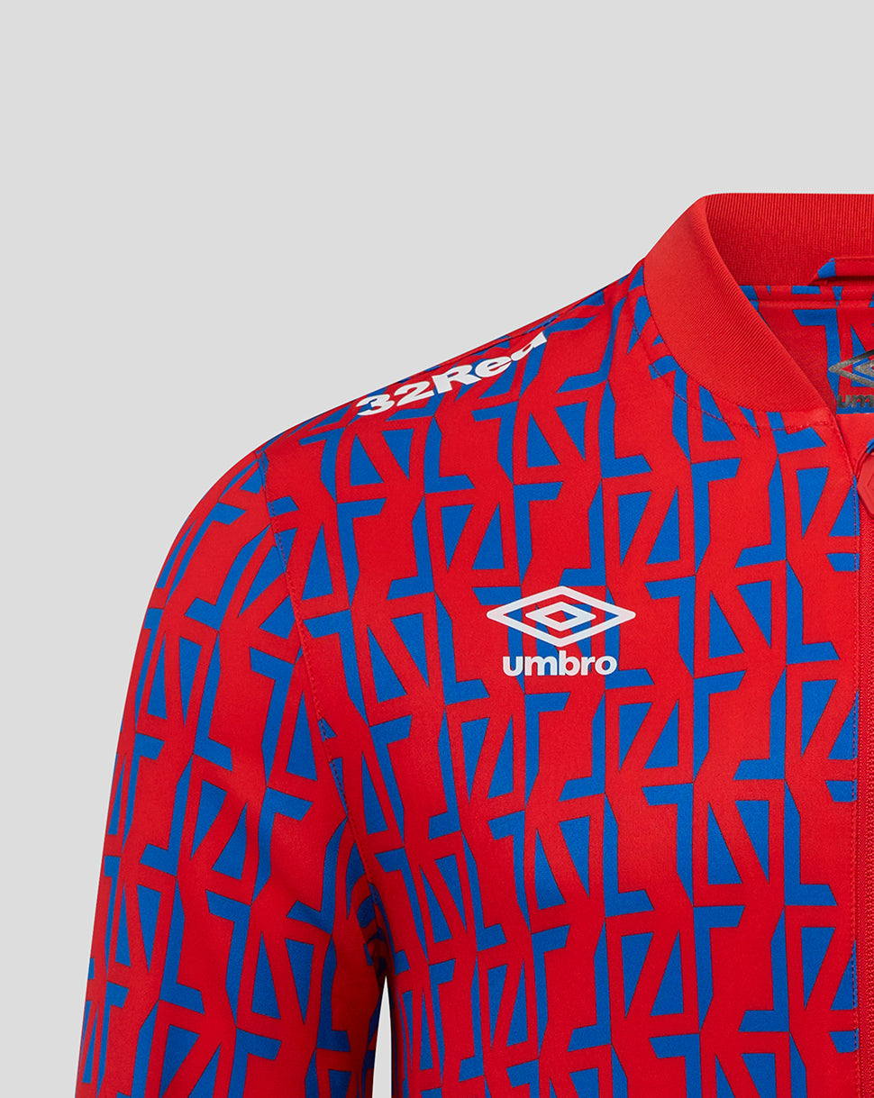 Shoulder close up of Rangers Men's 25/26 Away Matchday Jacket with red and blue geometric print and Umbro logo plus club crest.