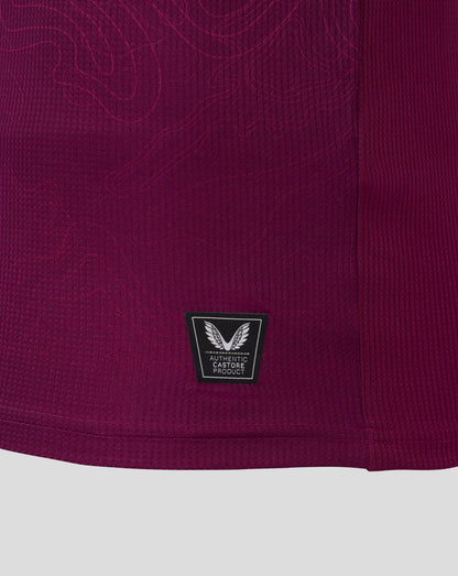 Close up of burgundy Burnley FC women's home shirt fabric with Castore authentic product badge.