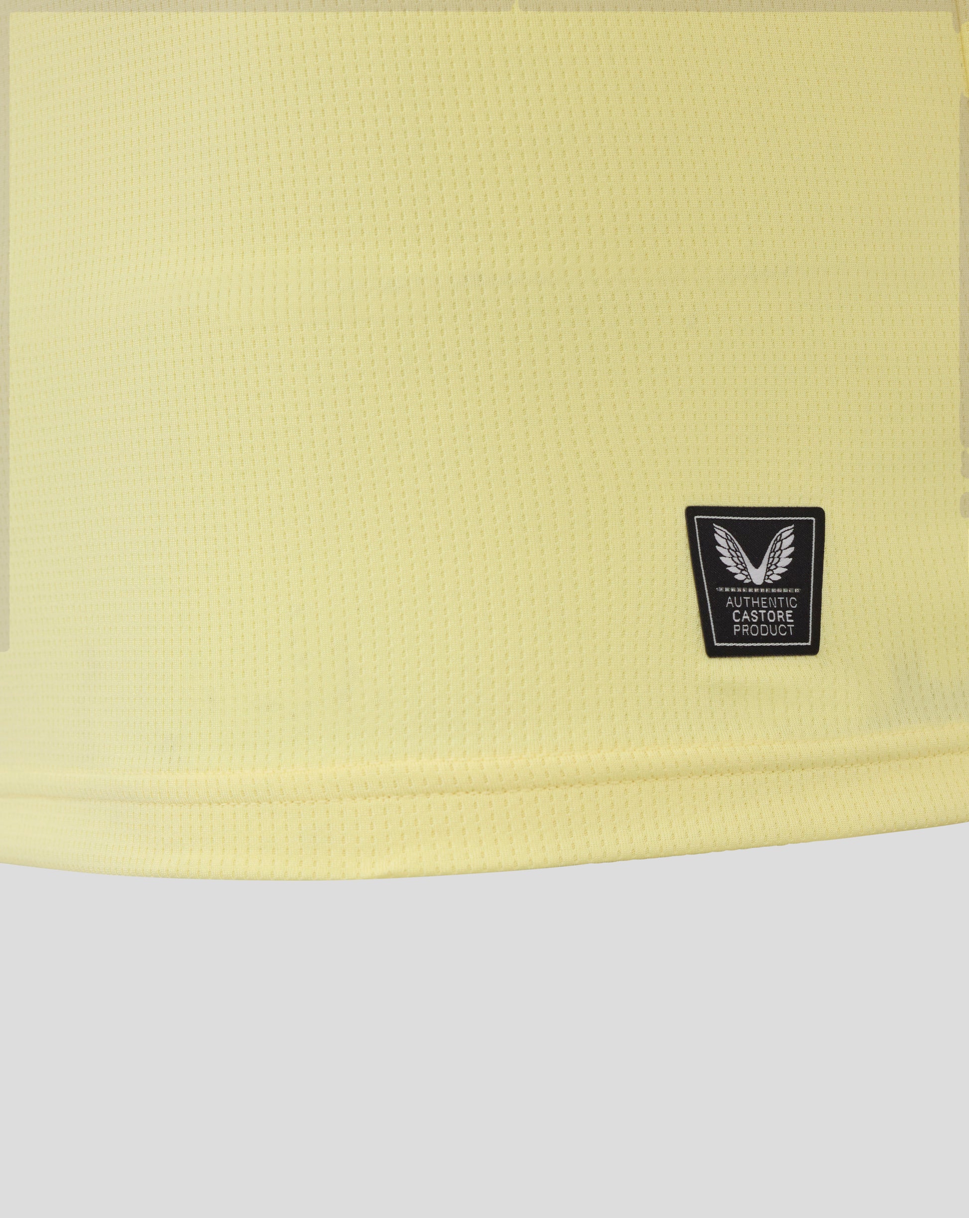 Yellow textured fabric of Everton junior away shirt with a winged crest patch in the lower right corner