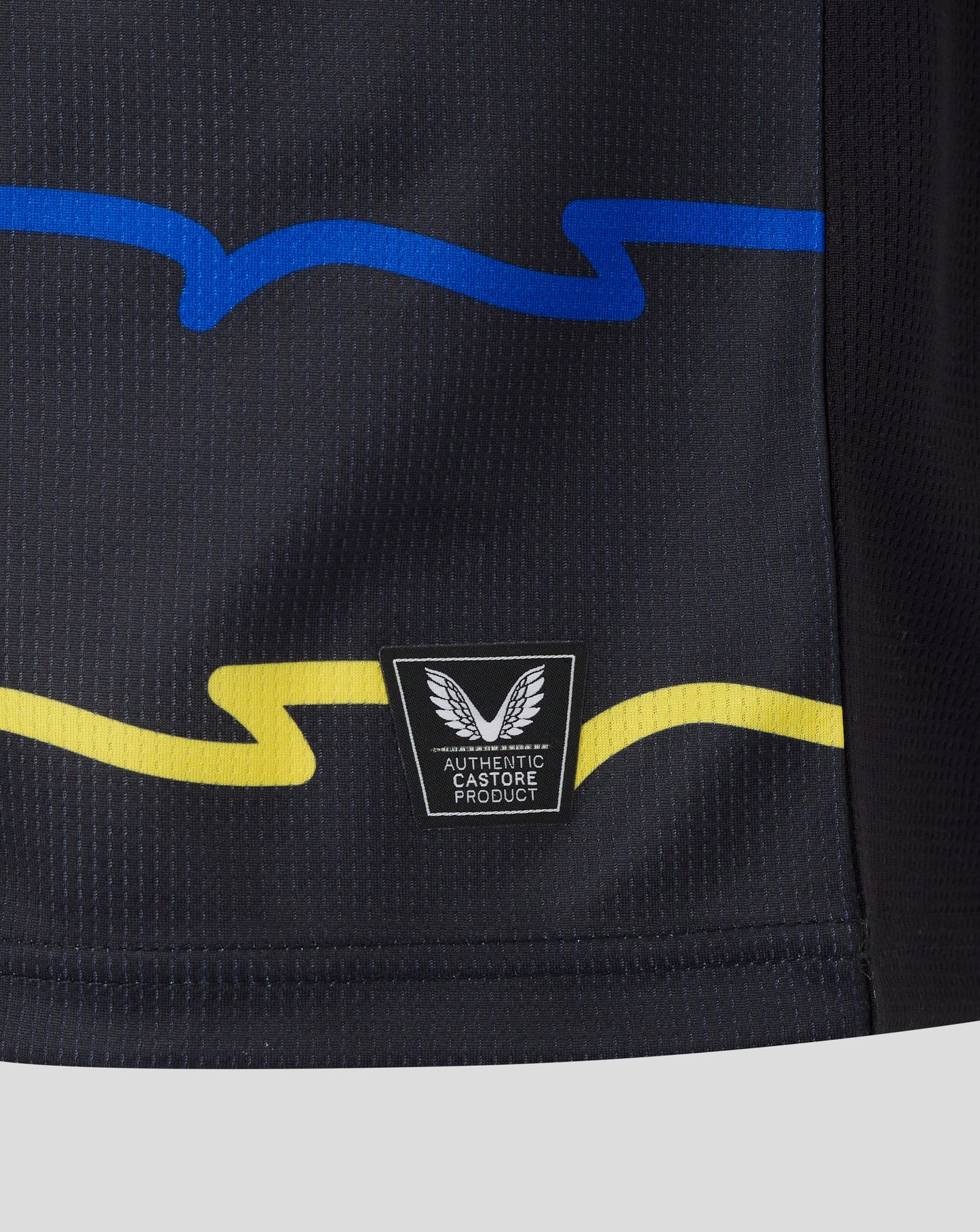 Close-up of Everton 25/26 Junior Third Shirt fabric with blue wave graphic and authentic Castore patch.