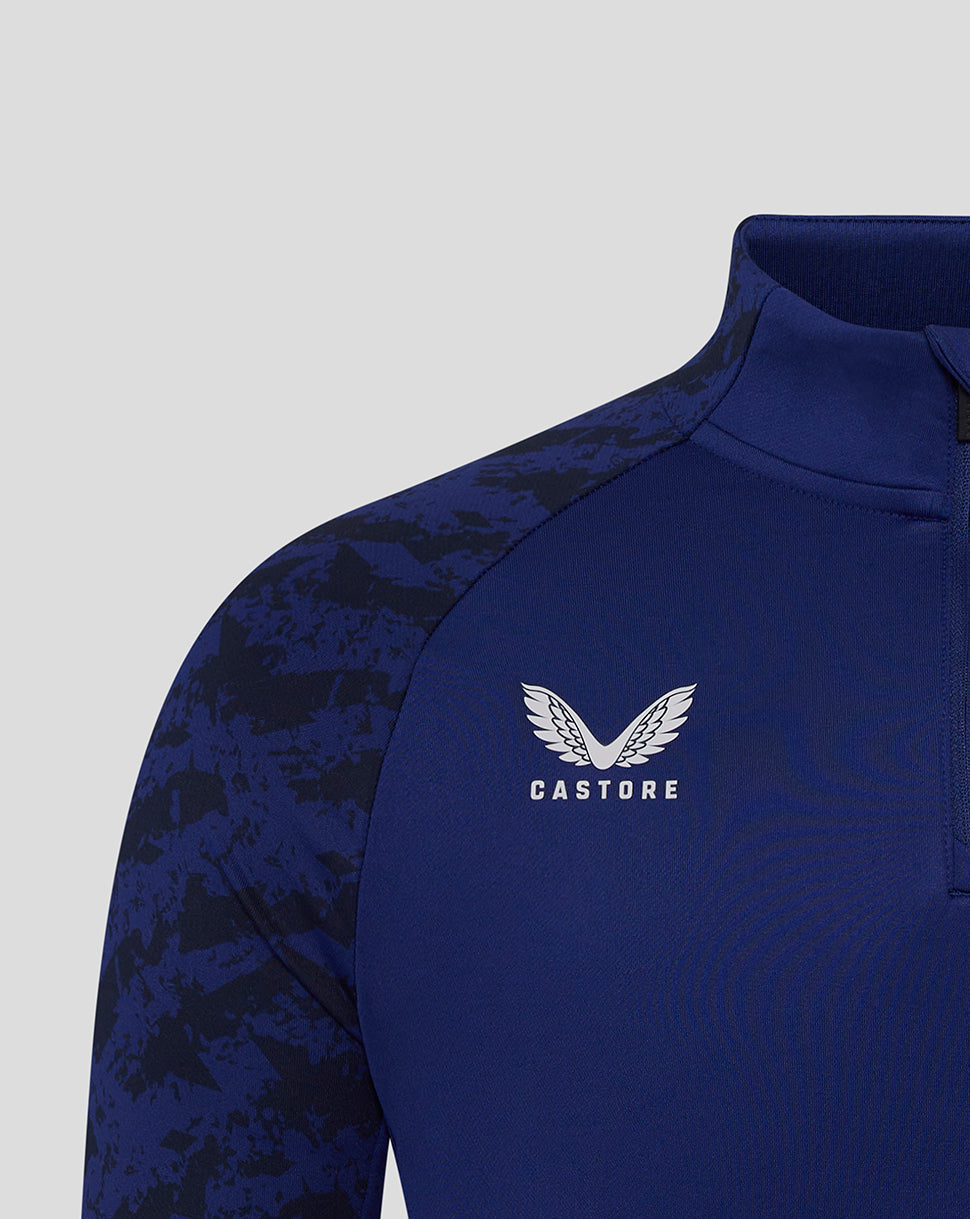 Close-up of Castore logo on the chest of the Preston Junior blue training midlayer with partial crest visible.