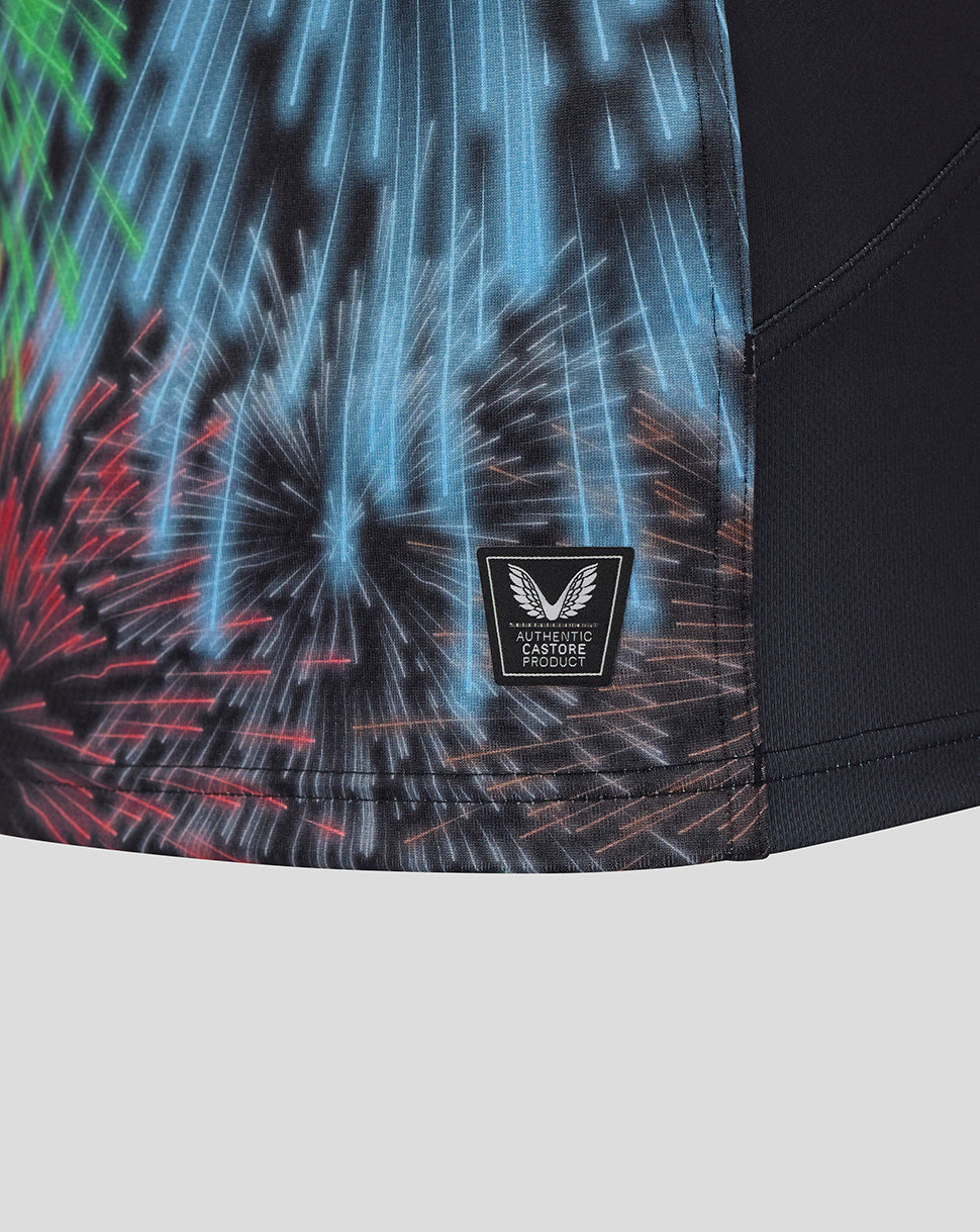 Lower front hem closeup showing authentic Castore product badge amid colorful fireworks print on Harlequins shirt