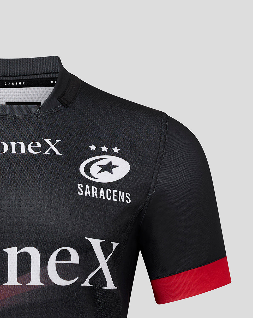 Close up of Saracens Pro Home Shirt chest showing crest, three stars, and oneX sponsor on black fabric with a red sleeve cuff
