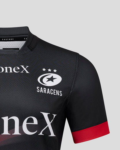 Close up of Saracens Pro Home Shirt chest showing crest, three stars, and oneX sponsor on black fabric with a red sleeve cuff