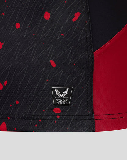 Close-up of black fabric panel with red paint splatters on a Saracens Showdown replica shirt and an authentic Castore badge