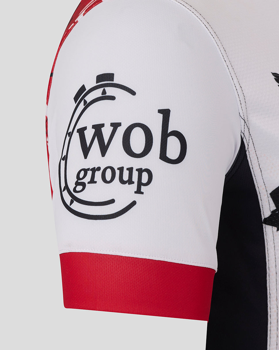 Close up of a white Saracens Showdown replica shirt sleeve with red cuff and wob group graphic