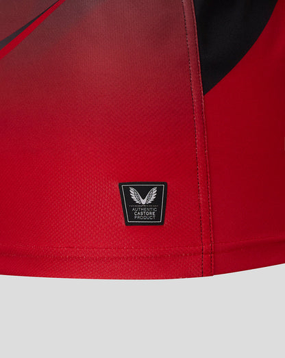 Close-up of red Saracens jersey hem with a small black Castore Authentic Product badge.