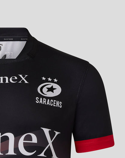 Front close up of black Saracens replica shirt with crest and large white sponsor text.