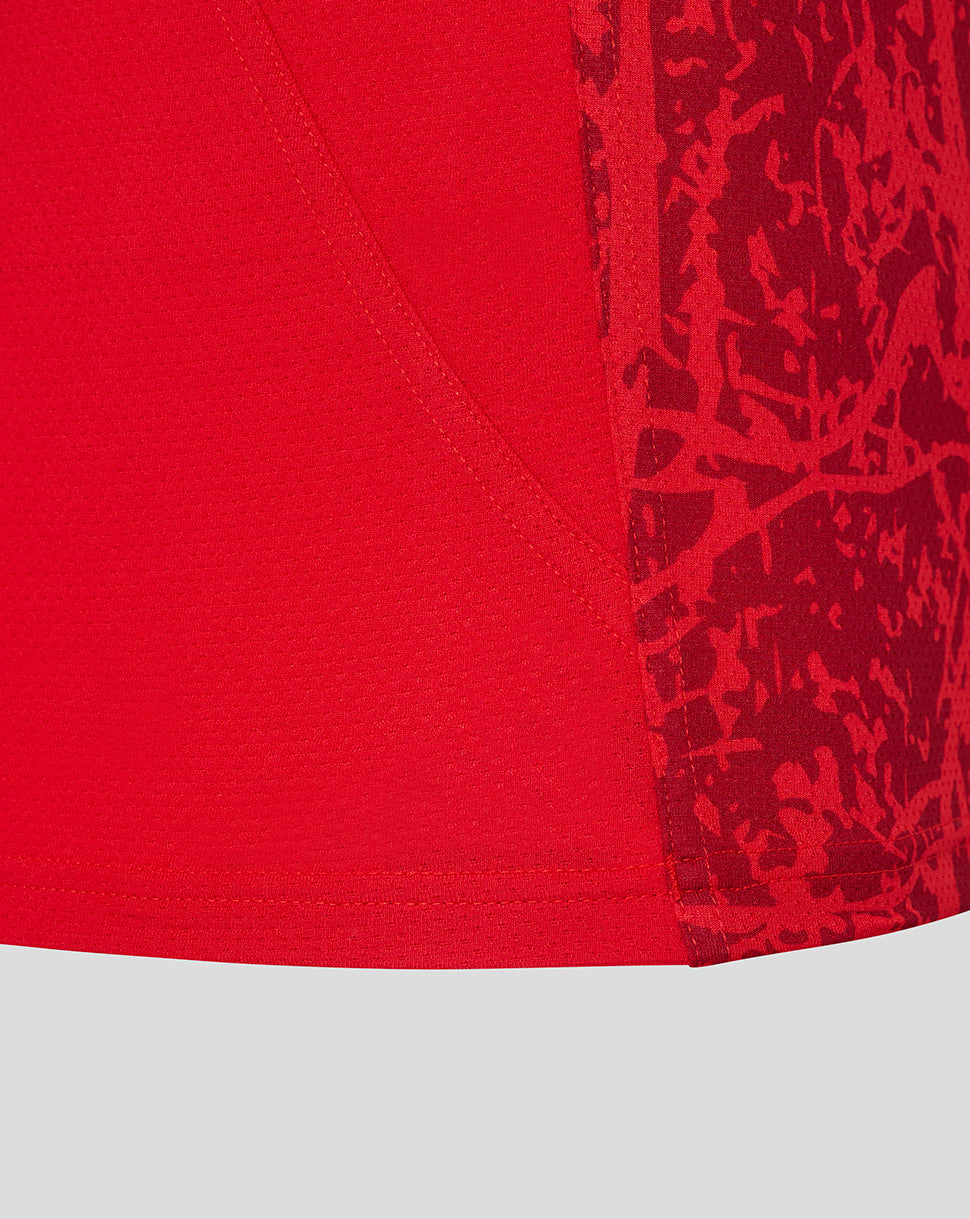Close-up of the tee's red fabric showing a stitched seam and a camo patterned side panel detail