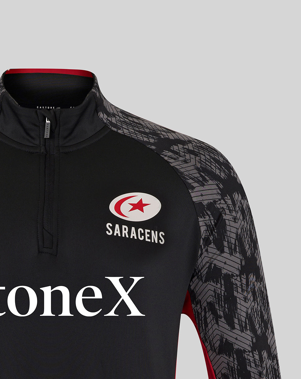 Close-up of black Saracens top showing crest on the chest and prominent StoneX branding across the front