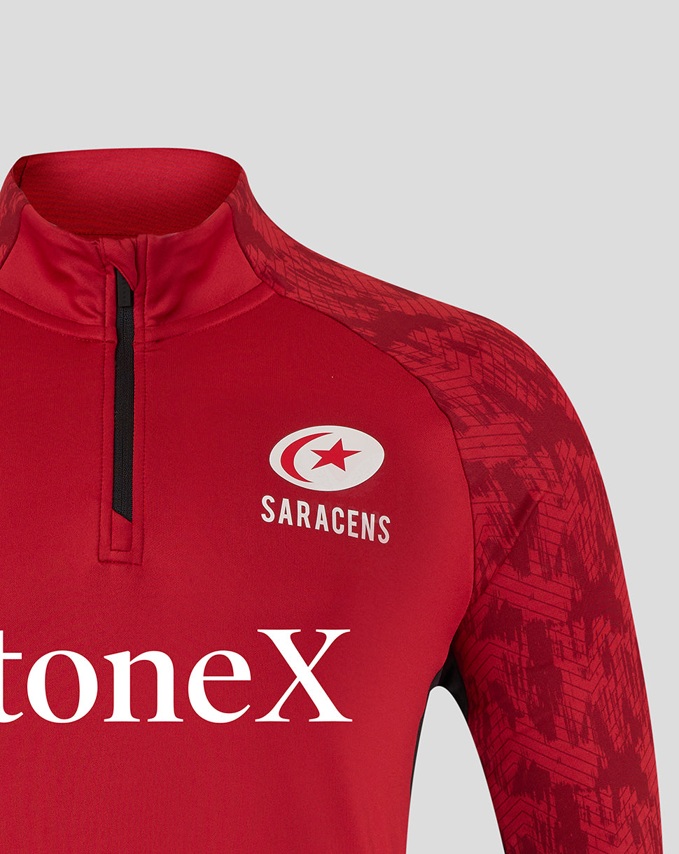 Close-up of chest area on red Saracens top showing the Saracens crest and the StoneX logo.