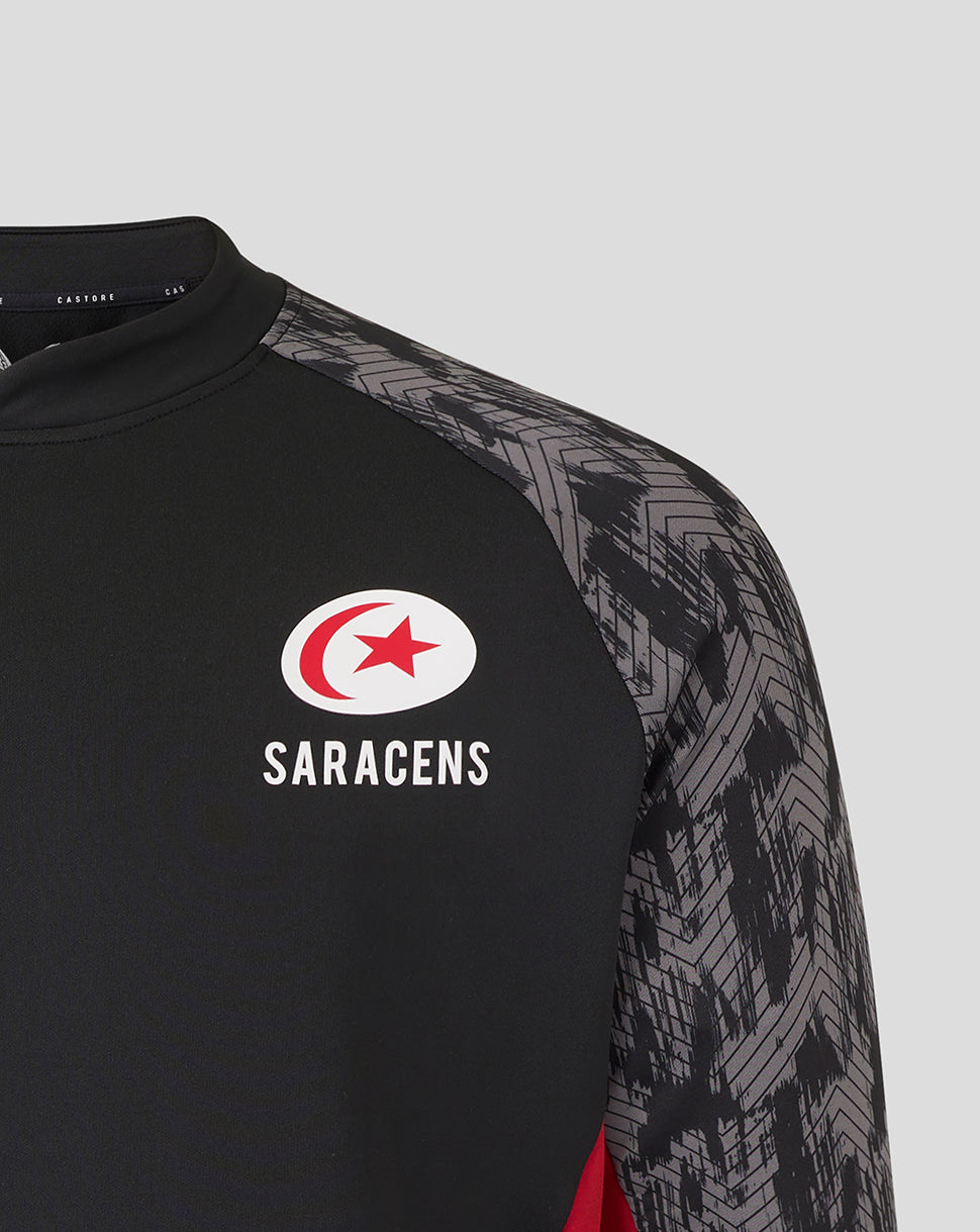 Close-up of the Saracens logo on a black drill top with grey patterned sleeves.
