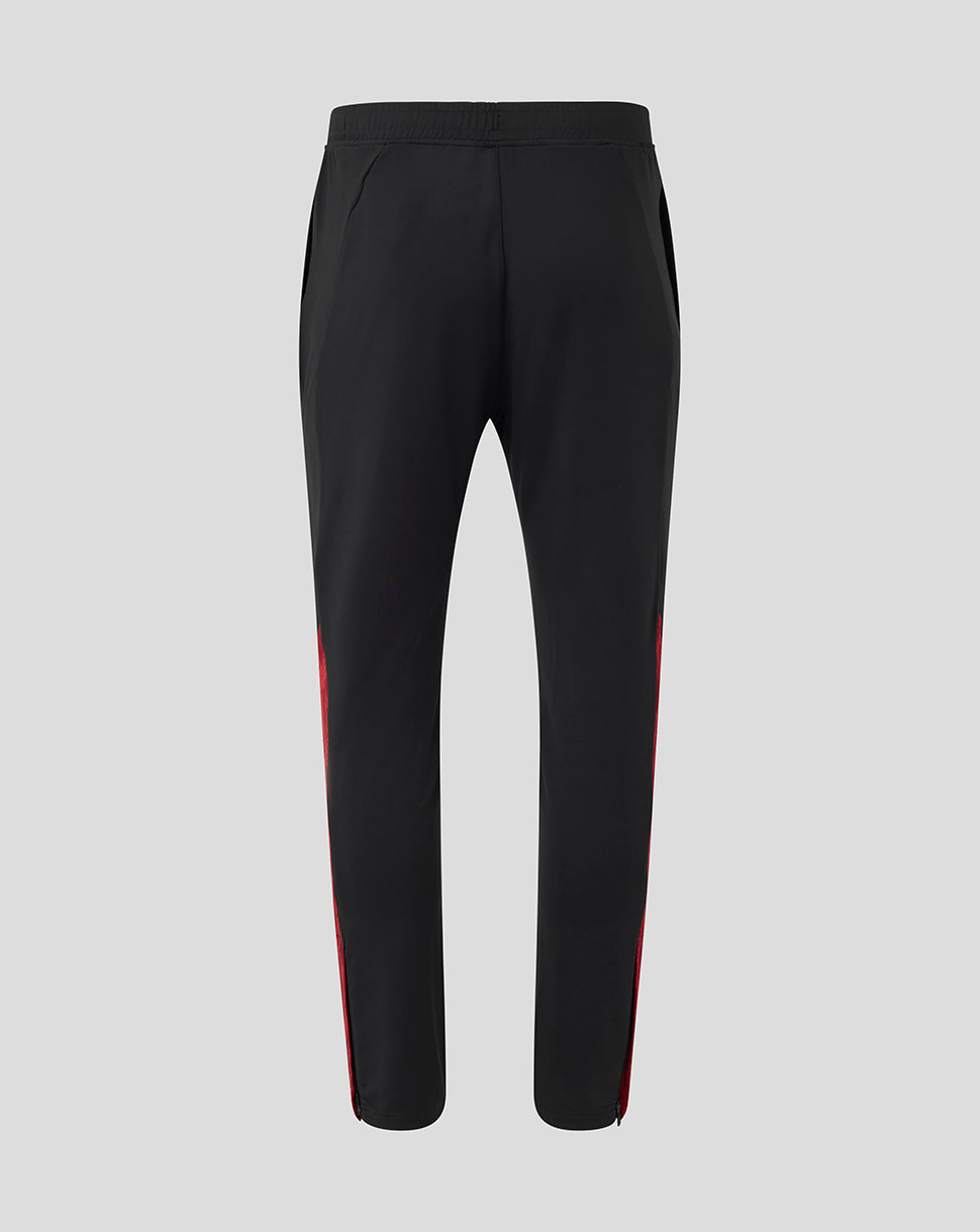 Back view of black training pants with red side stripes and tapered ankles.