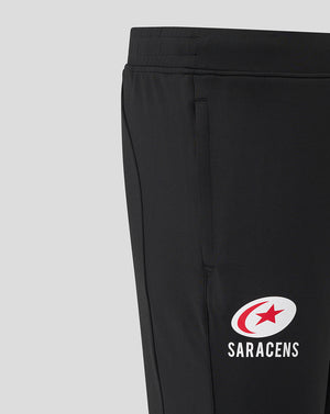 Close up of waist and pocket area on black Saracens training pants showing the elastic waistband and logo on the leg.