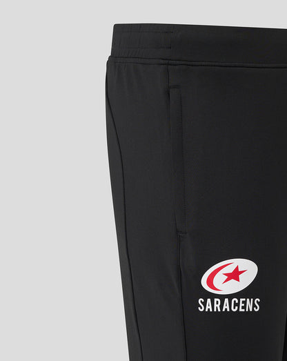 Close up of waist and pocket area on black Saracens training pants showing the elastic waistband and logo on the leg.