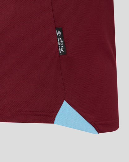 Close up of maroon fabric from a West Ham home shirt with a vertical black tag showing Official Licensed Product and the Umbro logo along the seam