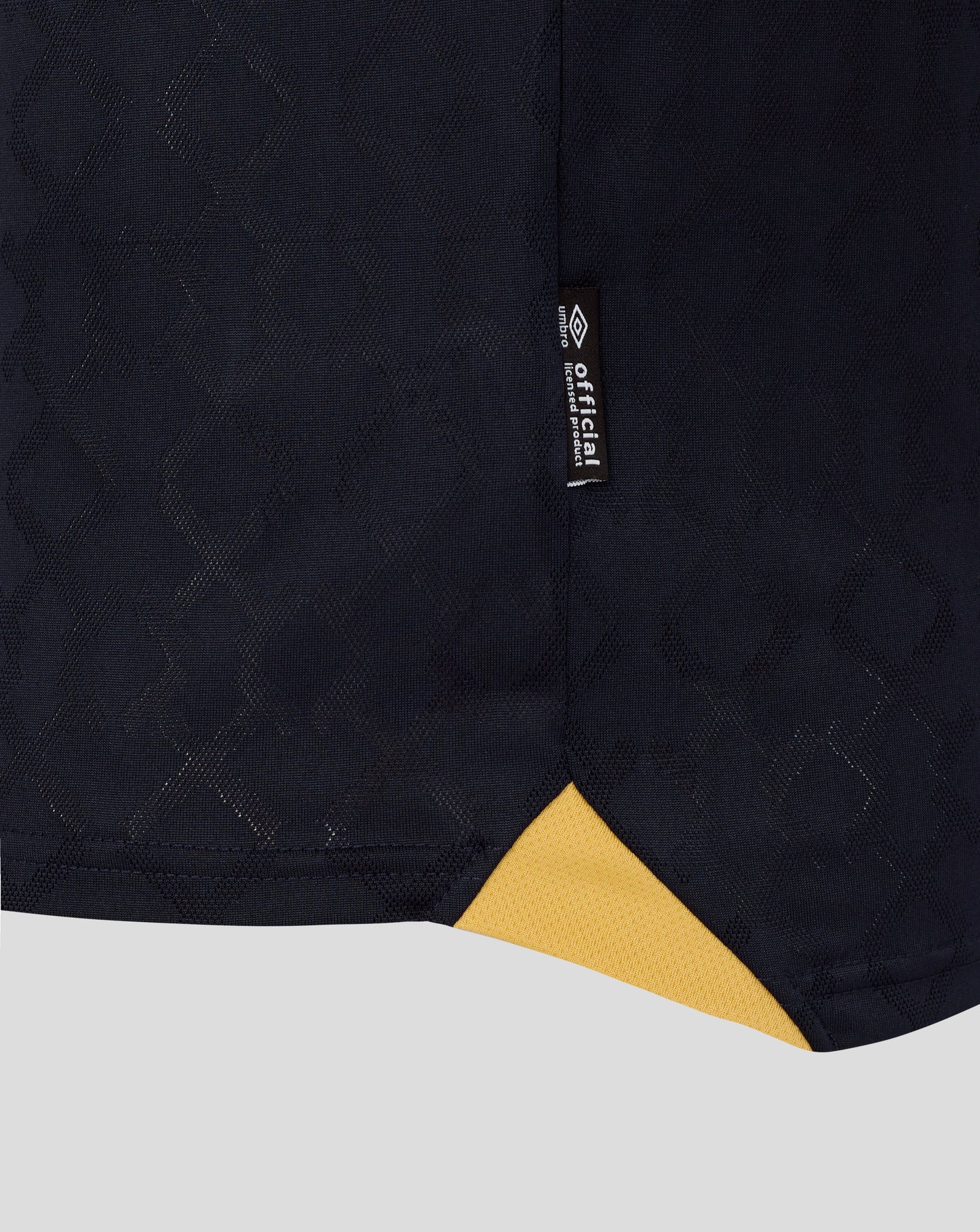 Close up of navy West Ham 25/26 third kit fabric with a subtle diamond pattern and a vertical official license tag.