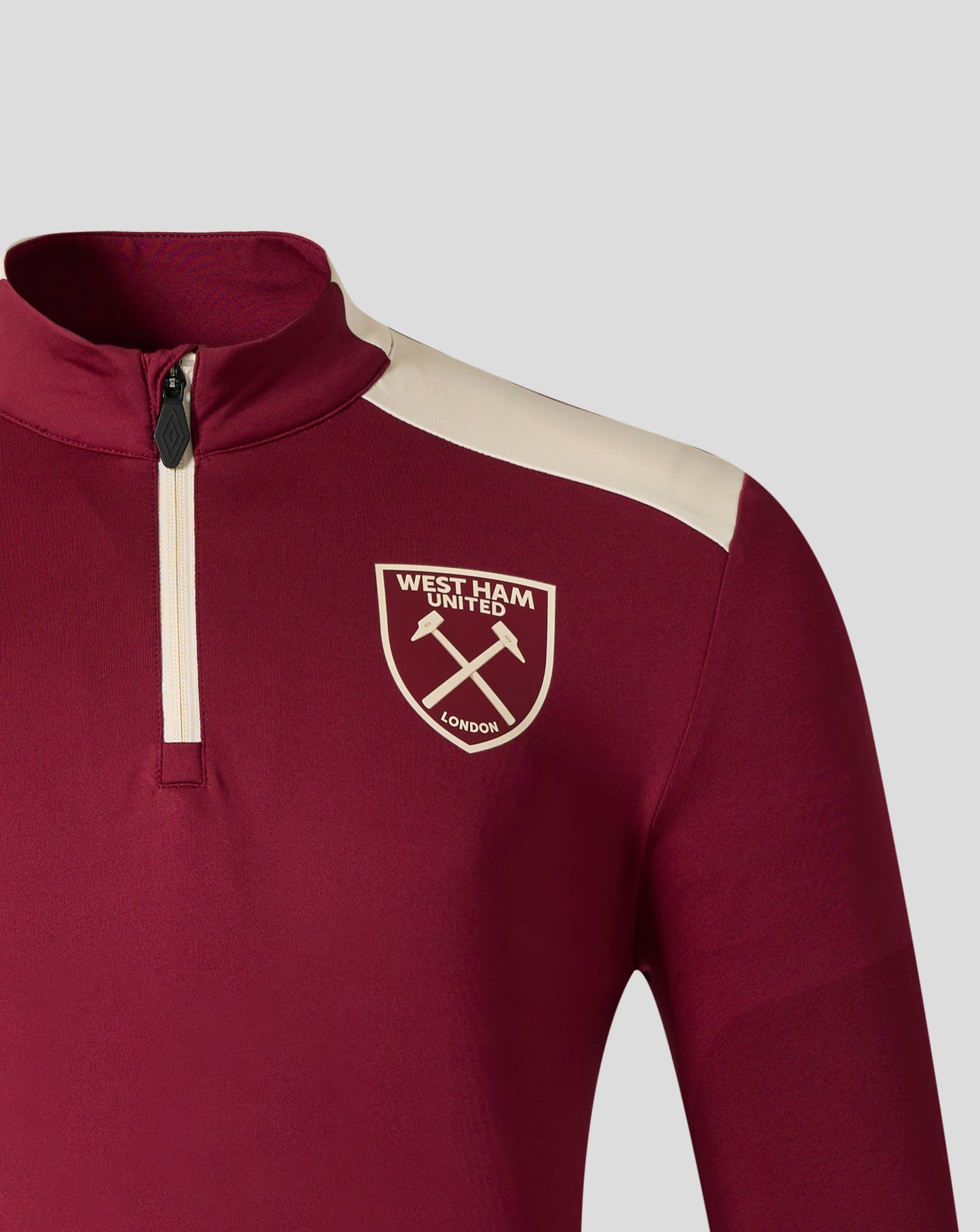 Close up of West Ham United training midlayer in rhododendron red with a beige shoulder stripe and front zipper