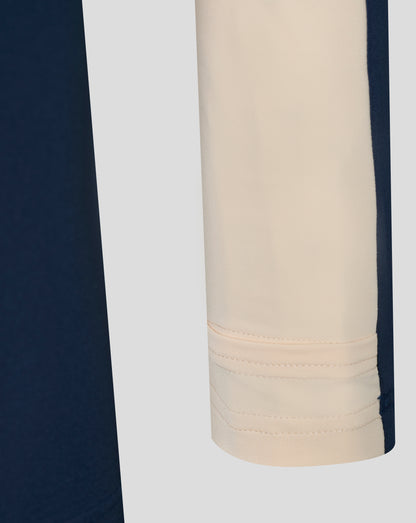 Beige side panel on navy training top with visible stitching and curved hem detail.