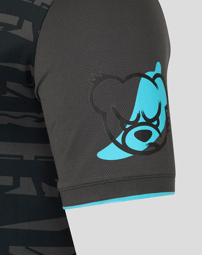Sleeve close up showing a turquoise bear graphic on dark fabric with turquoise cuff trim