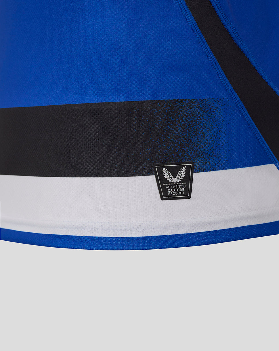 Close up of authentic Castore product badge on the Bath Rugby shirt hem with blue fabric and white stripe