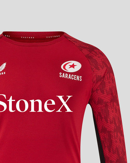 Close-up of Saracens training long sleeve tee in rhythmic red with crest and StoneX sponsor across the chest and textured fabric.