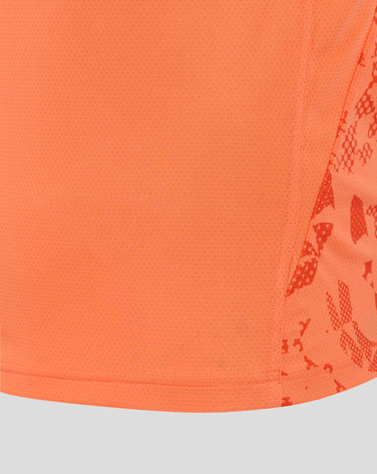 Close-up of bright melon mesh fabric from the England Rugby performance shirt, showing tiny perforations and a curved hem with partial side print