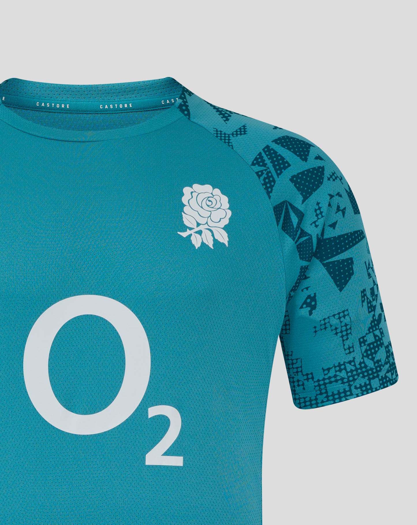 Close-up of Storm Blue England Rugby training shirt showing white rose crest on left chest and geometric patterned sleeves