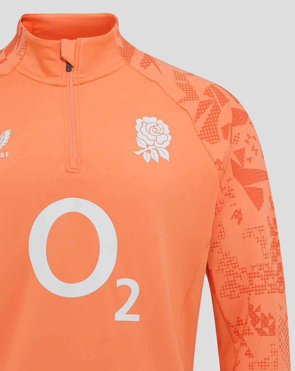 Front close up of melon long sleeve midlayer showing funnel neck quarter zip with rose crest on left chest and Castore logo on right chest.
