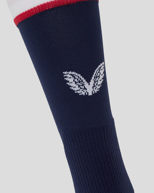 Close up of navy mid calf sock showing large white Castore wing logo and striped cuff