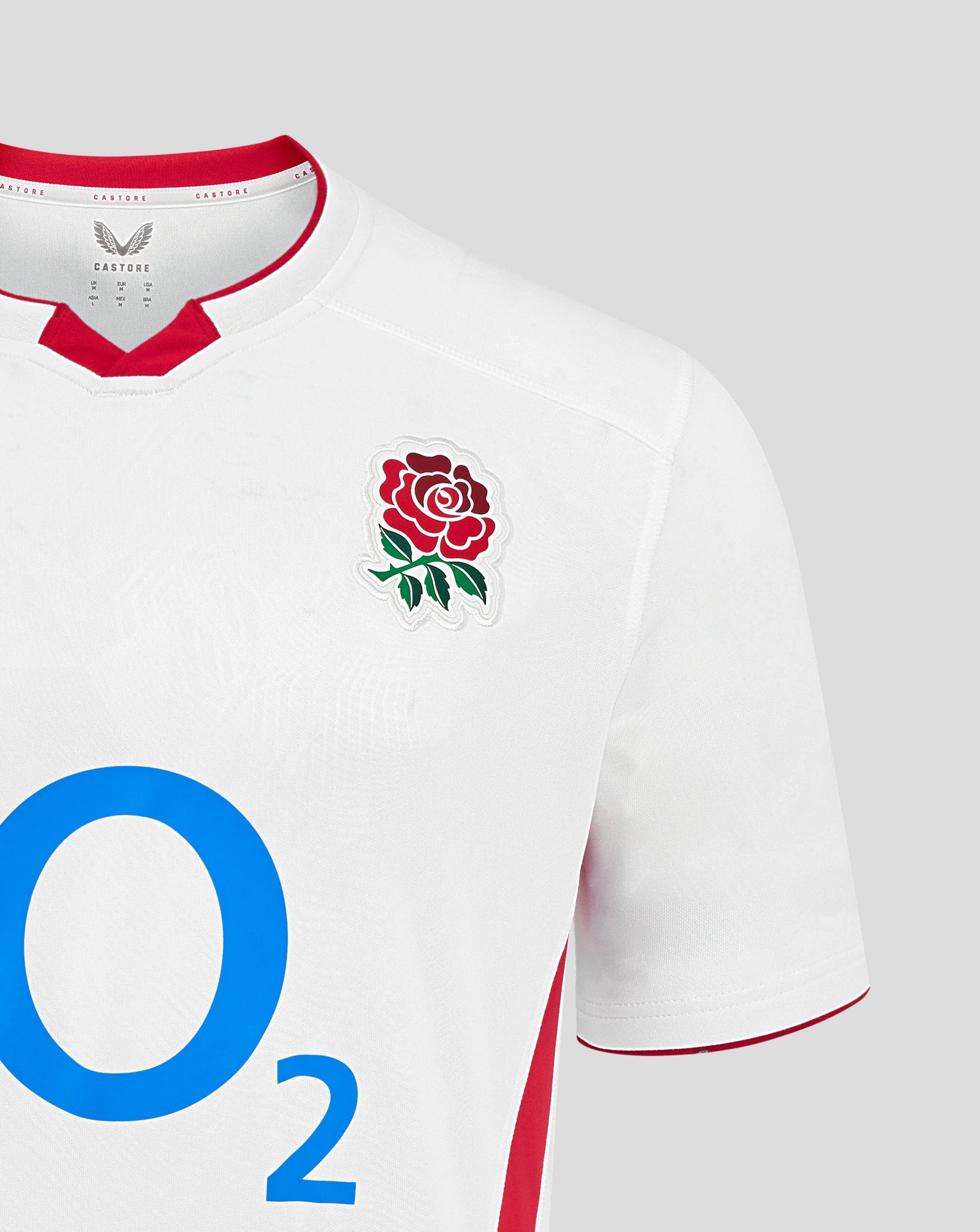 Close-up of white England rugby home shirt front showing embossed geometric design red collar trim left chest rose crest center O2 logo and Castore logo right chest