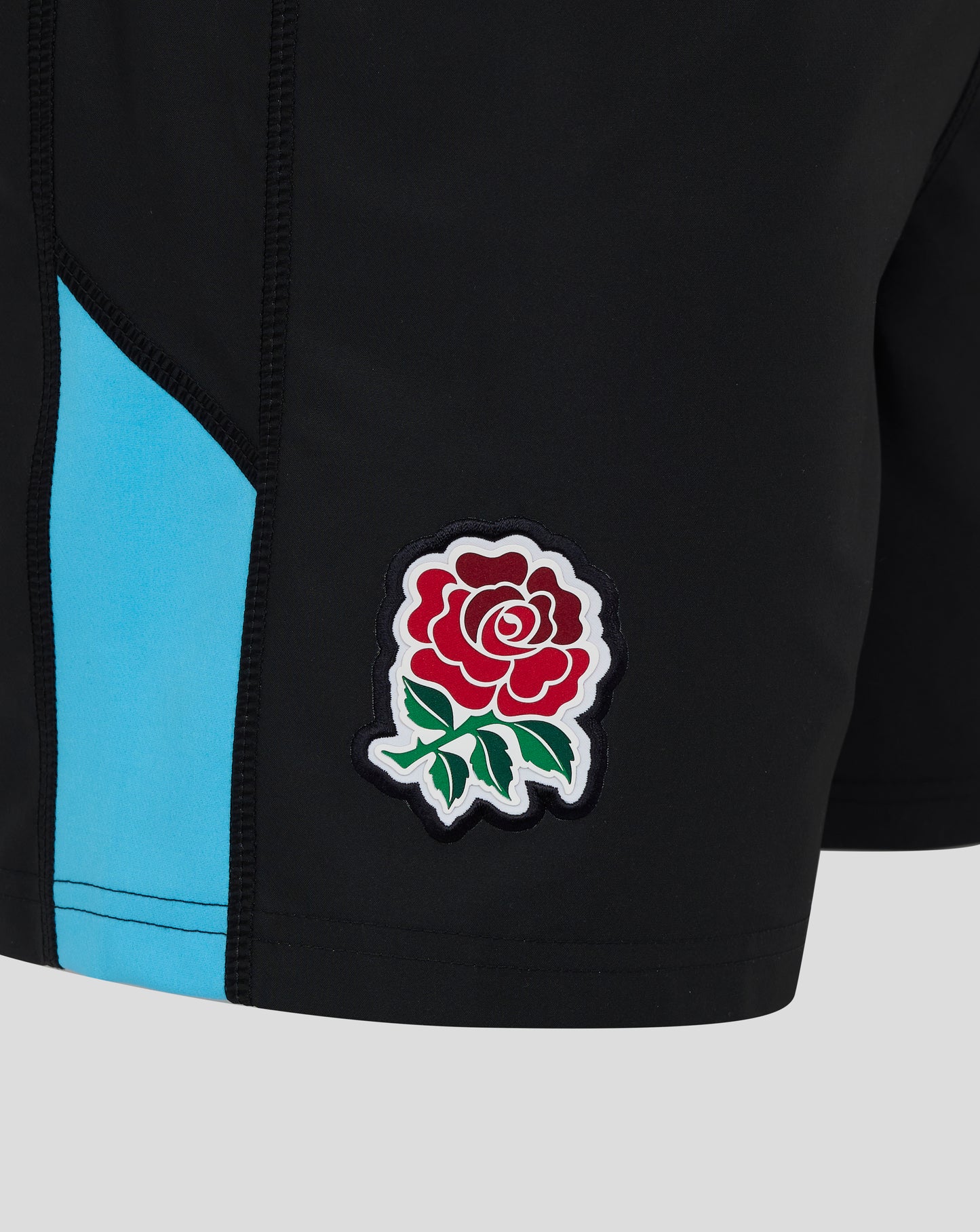 Close up of left leg with blue side stripe and red rose patch on black England rugby shorts