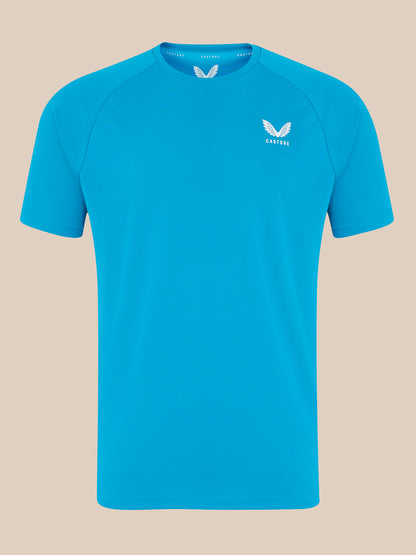 Front view of bright blue Castore logo T shirt with white wing emblem on the left chest.