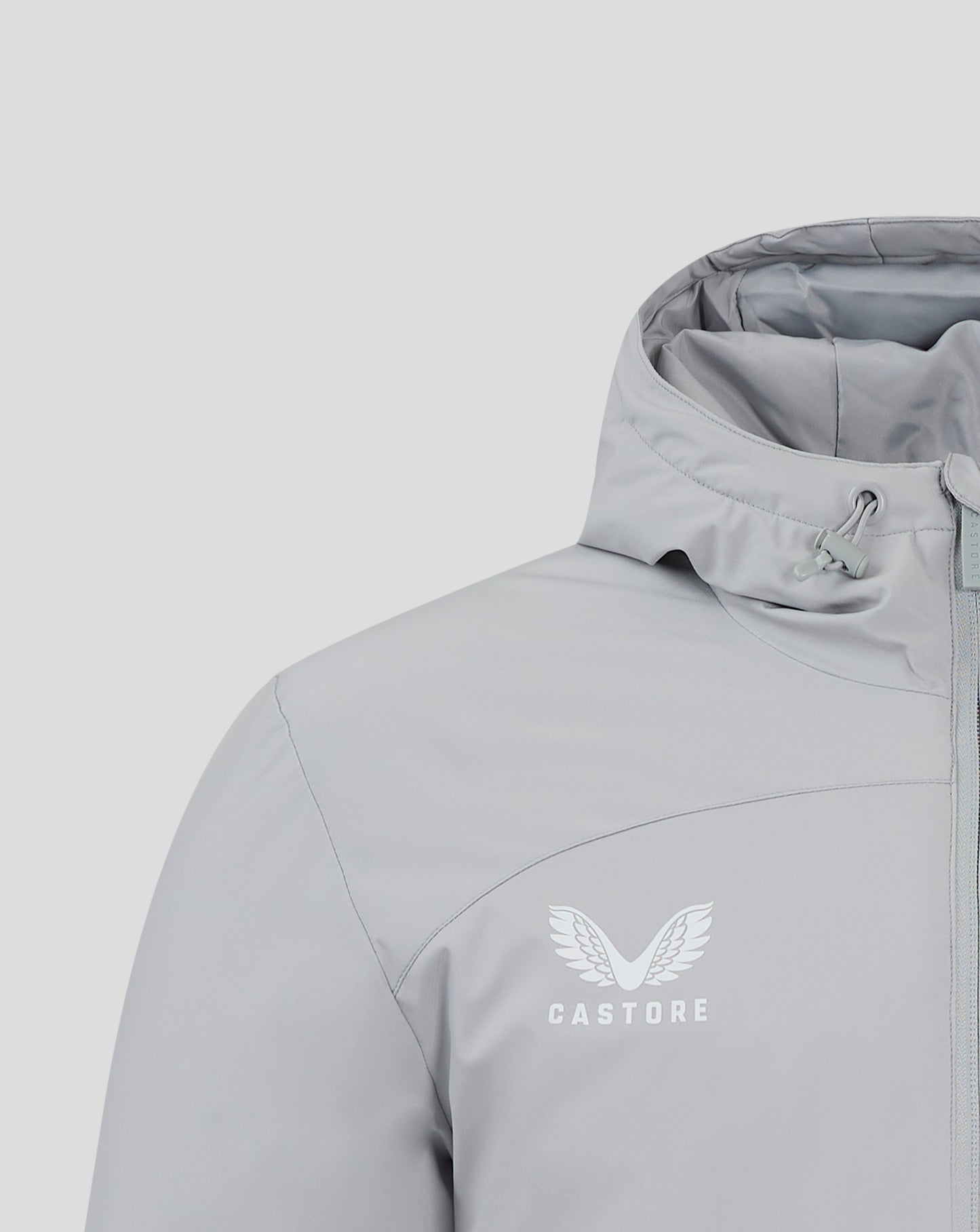 Close up of chest area with winged Castore logo on light gray Bench Jacket