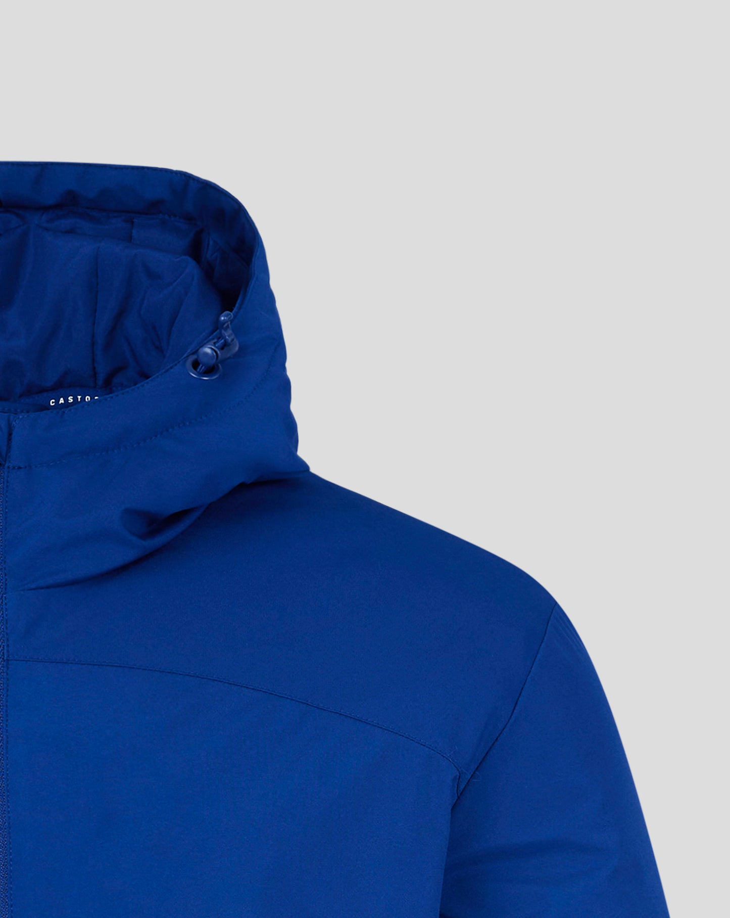 Close up of blue padded hooded jacket showing hood edge, drawcord toggle, and Castore logo