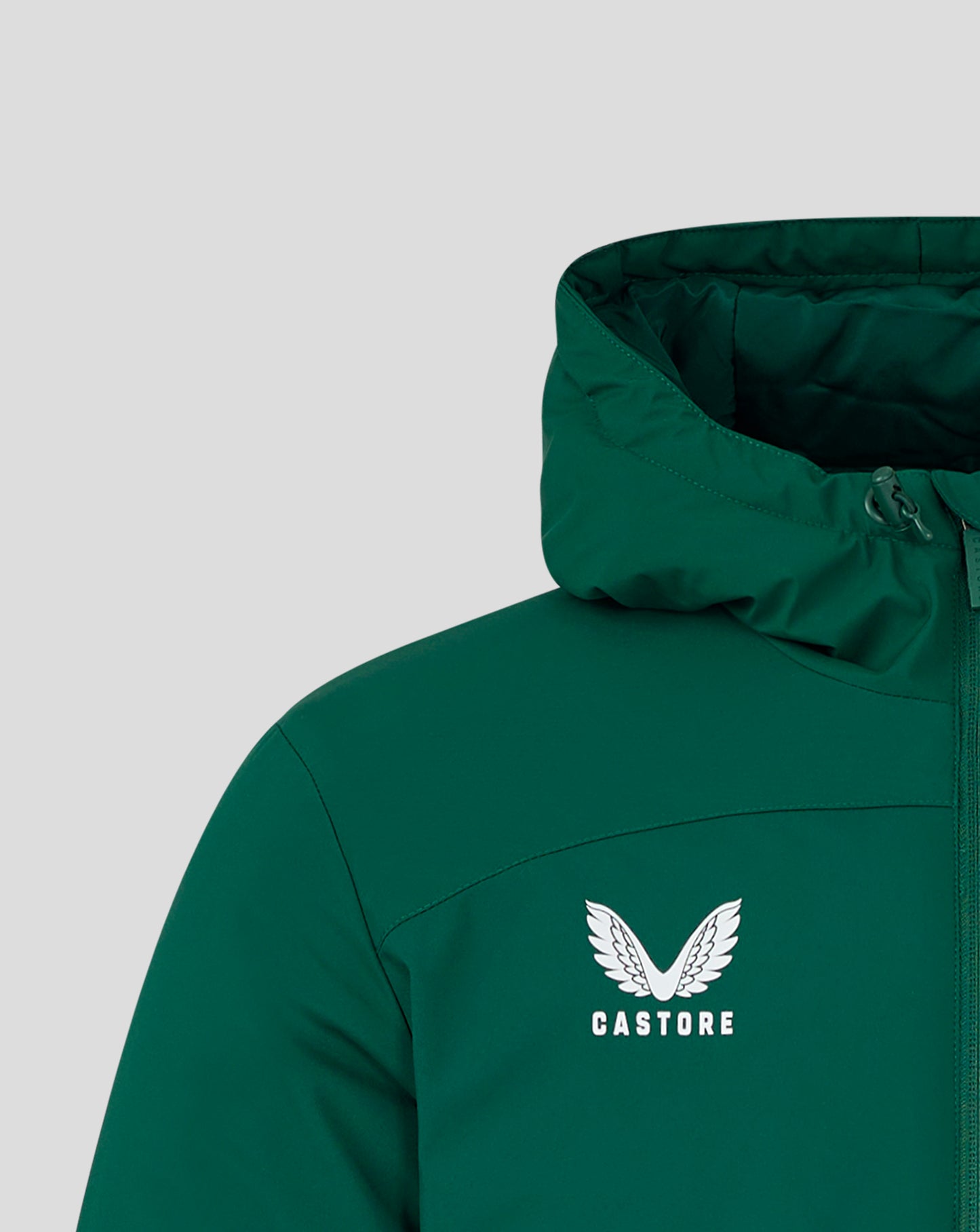 Close-up of green hooded bench jacket showing the Castore logo and wing emblem on the chest